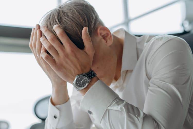 A Man Places His Hands on His Head in Distress
