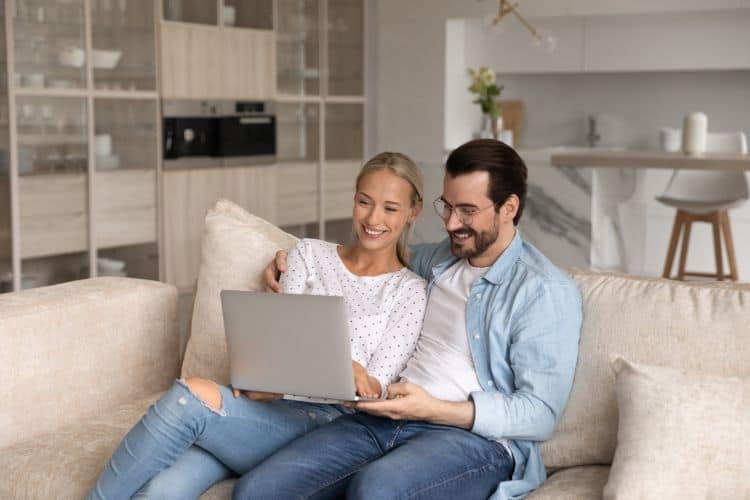 Happy couple renters relax at home with laptop