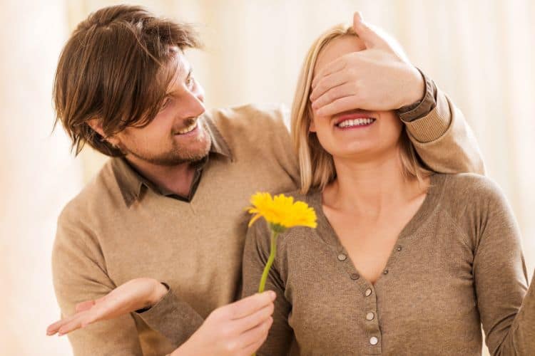 Husband surprising his wife with a yellow flower