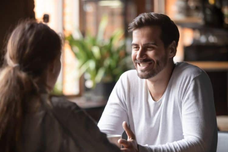 Rear view female sitting at a cafe with smiling man