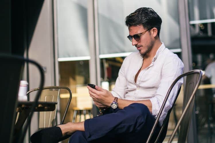 Young man sitting at a cafe and texting on his phone