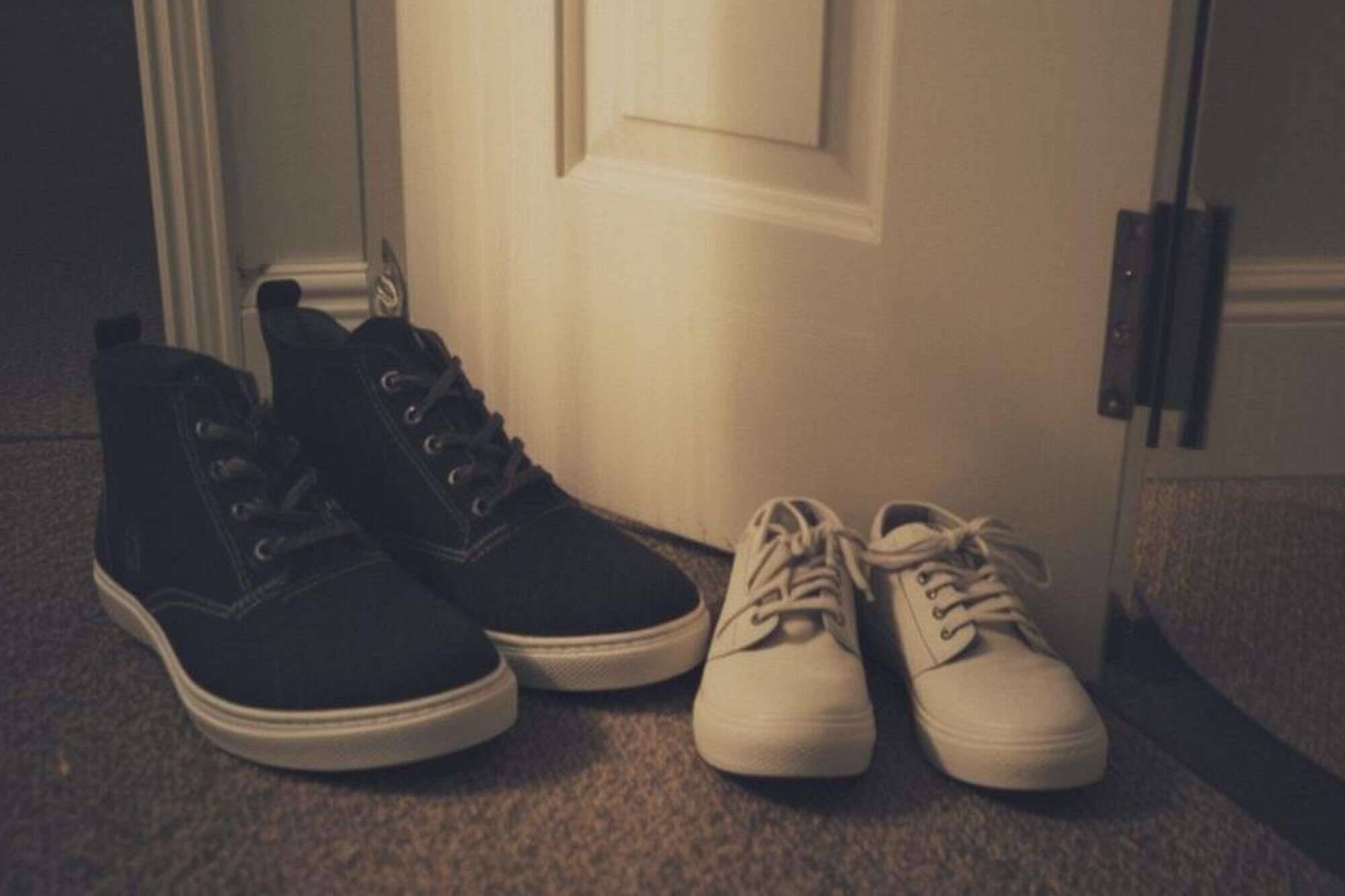 A grainy, high-contrast photo of an adult's shoes next to a child's shoes in a hallway, representing the quiet integration of a new partner into a family's life.
