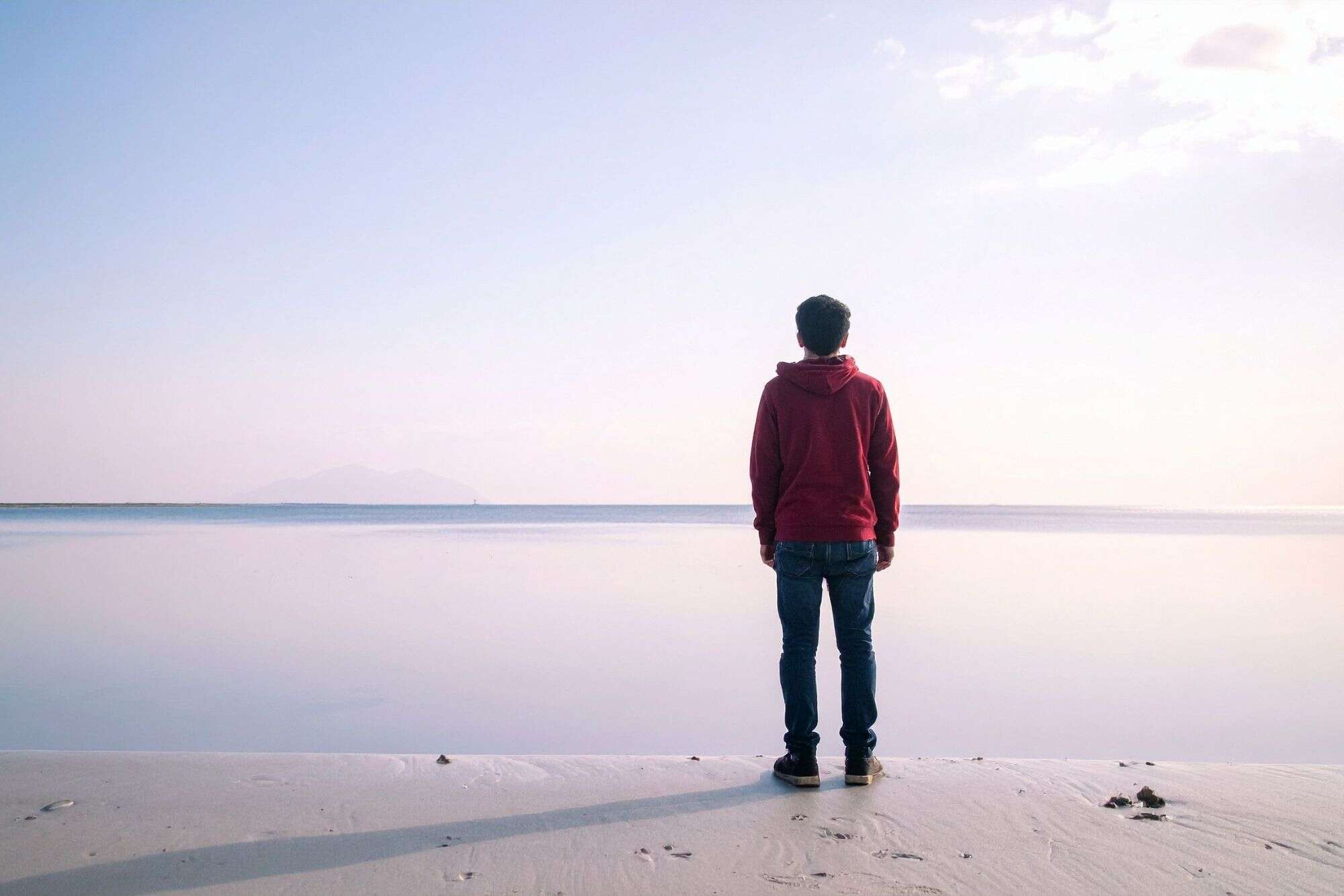 A man standing on a beach looking out at the ocean, representing the peace and confidence found in being true to one's own character.