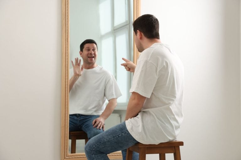 A man looking into a mirror, symbolizing the "nice guy narcissist" and the duality of polite behavior versus hidden intent.