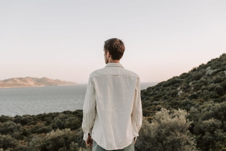 A thoughtful man with a beard standing quietly in a forest, representing the deep processing and introspective nature of the Highly Sensitive Person (HSP) male.