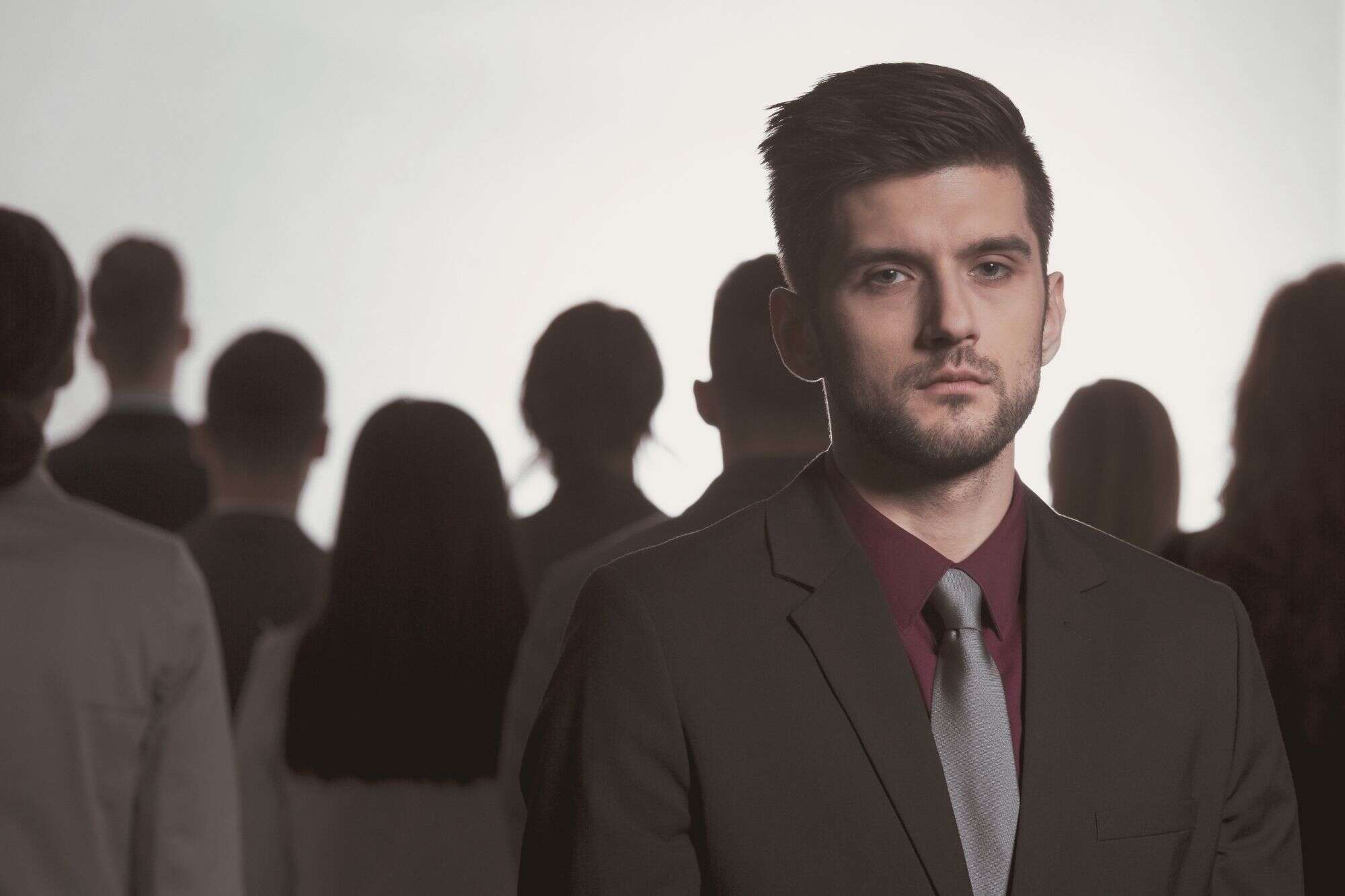 A focused man standing in the foreground with a blurred social crowd in the background, illustrating the rejection of social hierarchies.