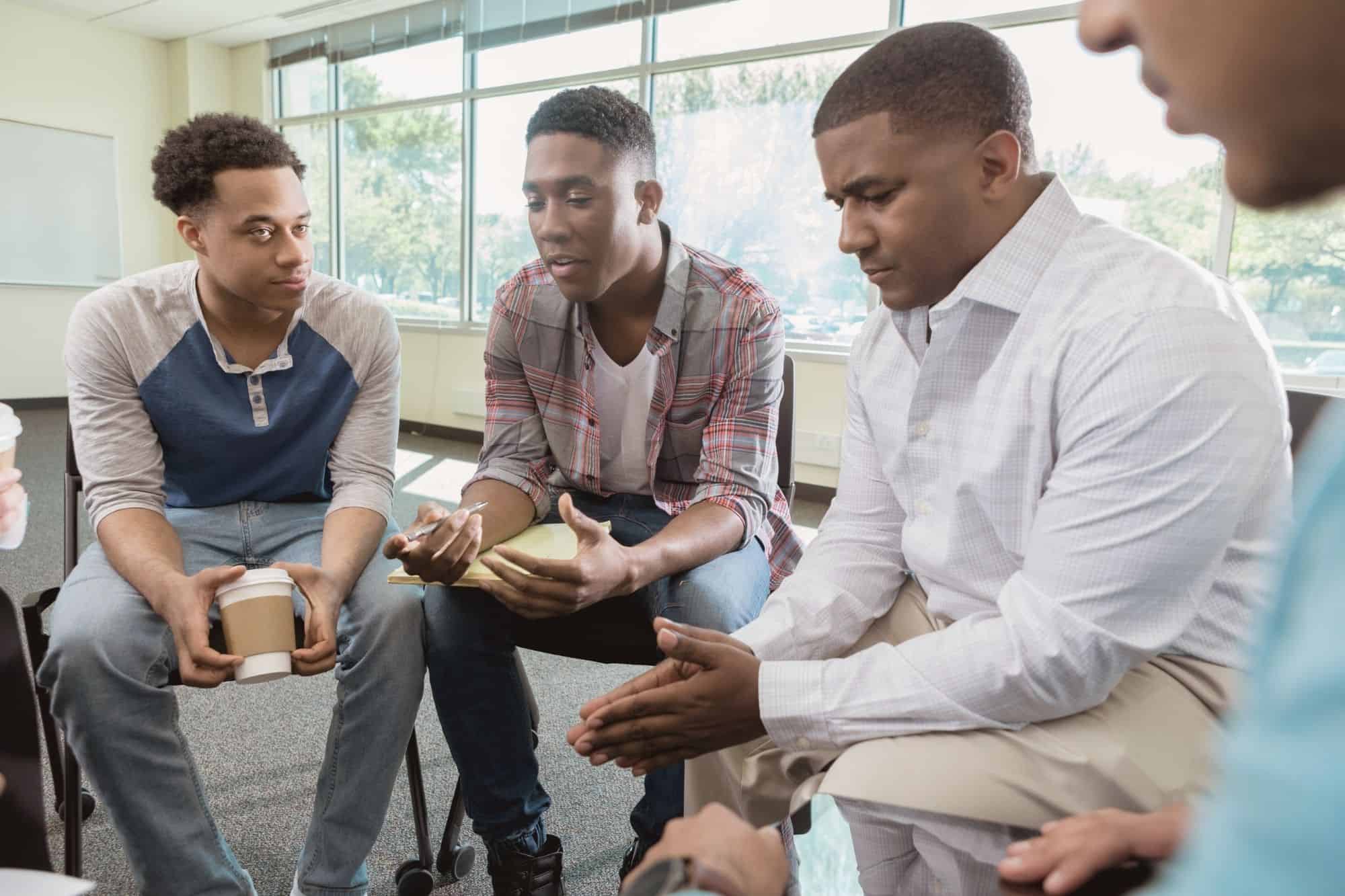 A group of men sitting together and talking in a supportive, high-integrity environment, illustrating the importance of a like-minded community.