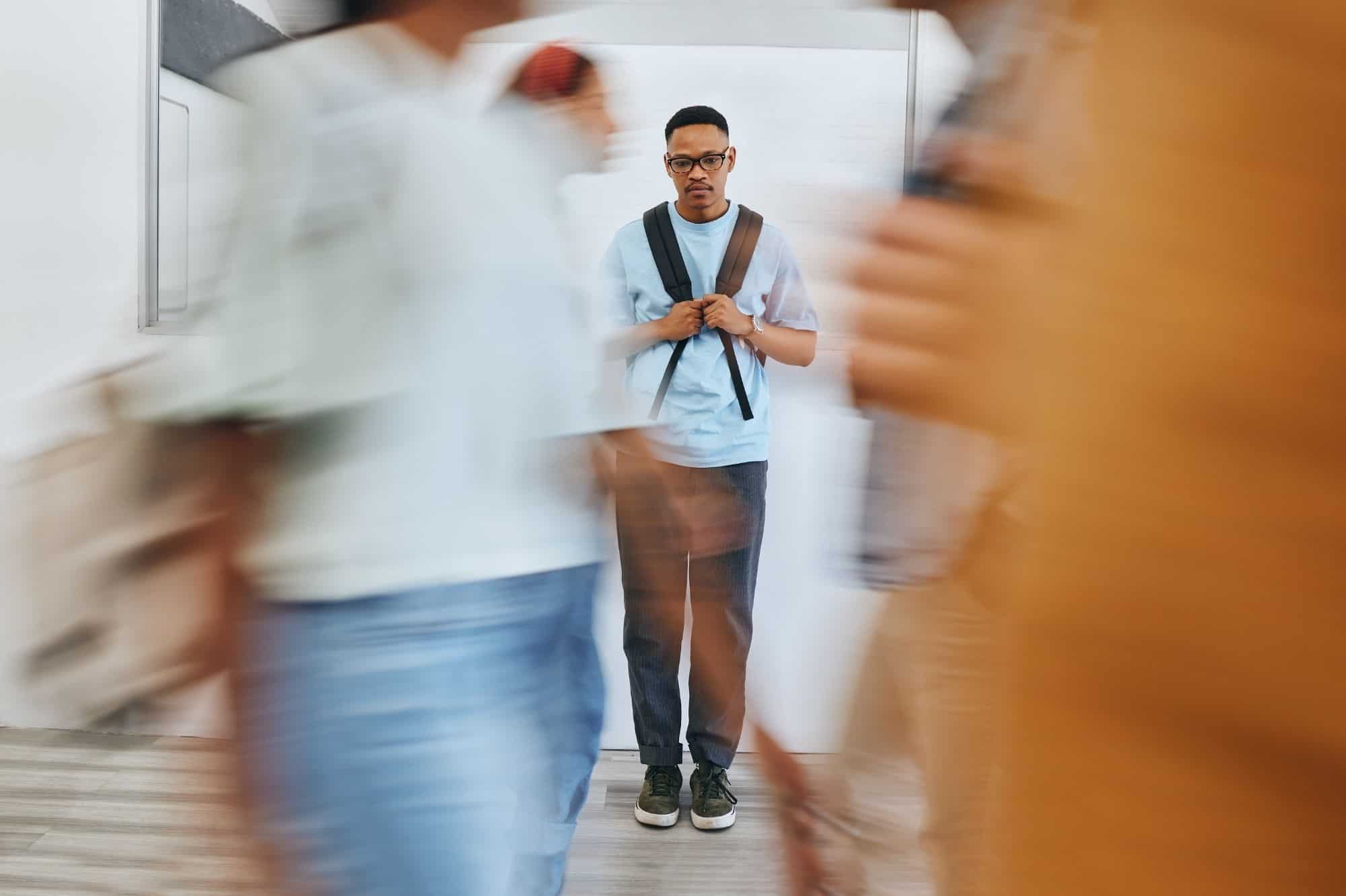A man looking overwhelmed and needing space while standing on the edge of a busy crowd, illustrating the sensory sensitivity of a Sigma empath.