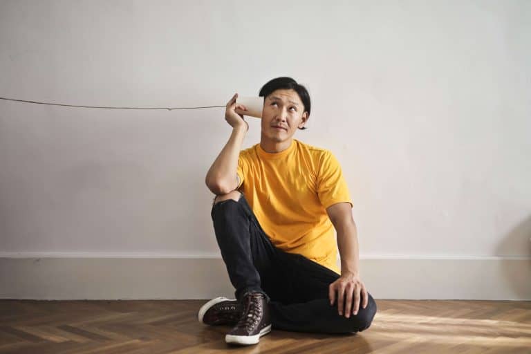 a man listening to a string makeshift telephone